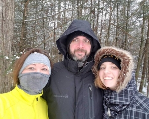 Active-living mentor Levi Moore poses with wife on daughter during a winter hike.