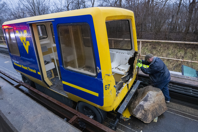 A maintenance worker inspects a wrecked PRT at West Virginia University.