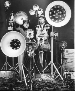 Link and an assistant display some of the specialized equipment employed in photography.