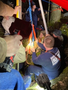 Rescuers hoist a dog out of the mouth of the cavern. 